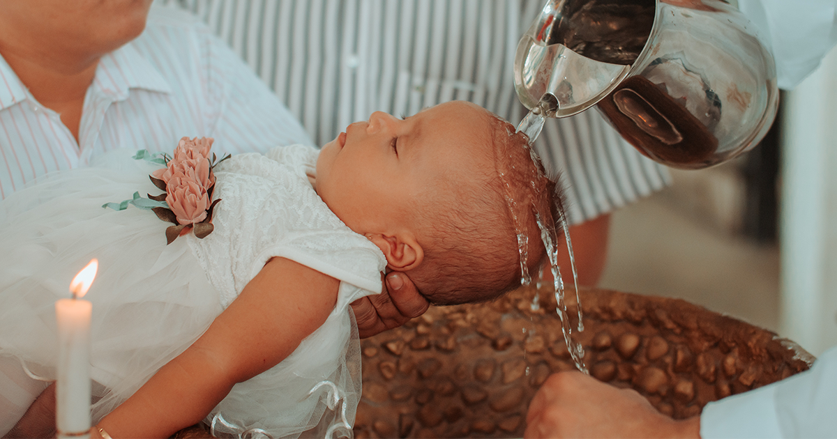 Holy water is poured over a baby's head as she is baptized.