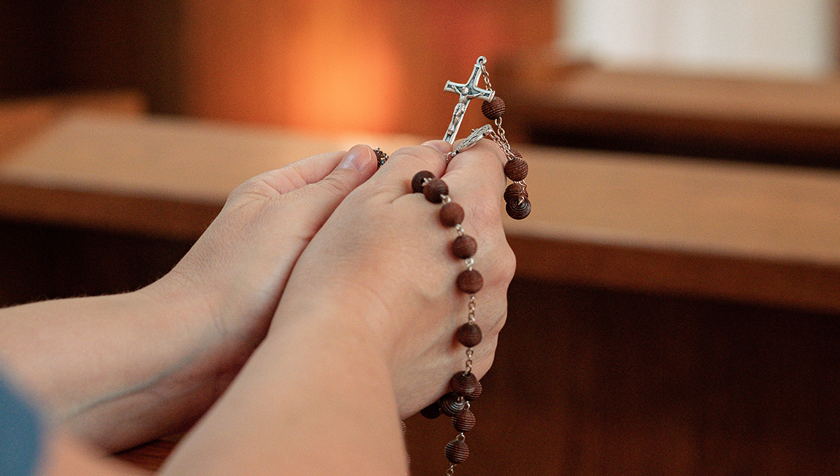 praying hands holding rosary
