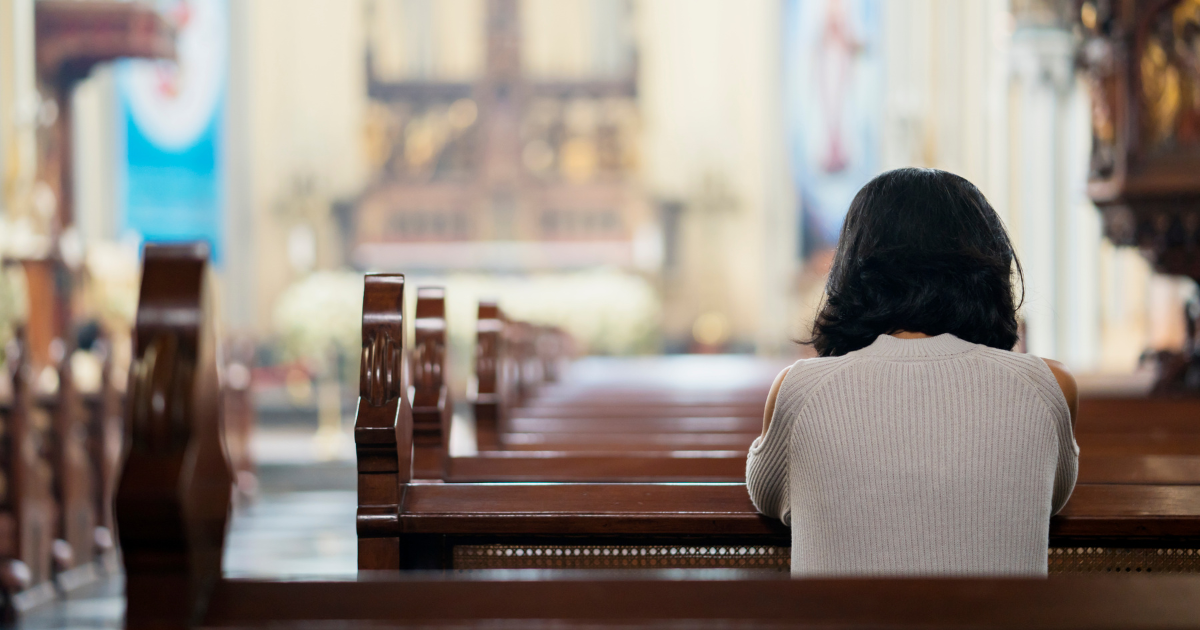 woman sits alone in back of church