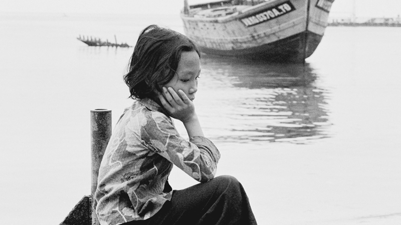 Vietnamese girl sits by herself near a boat