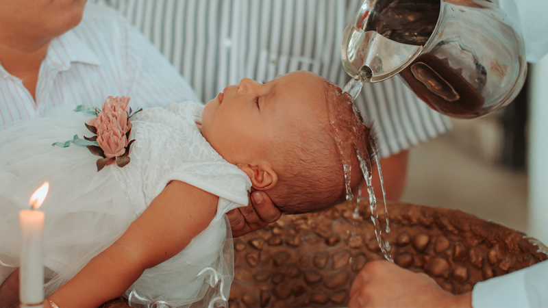 Holy water is poured over a baby's head as she is baptized.