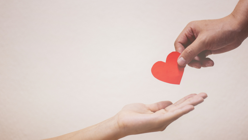 on person hands another person a paper heart