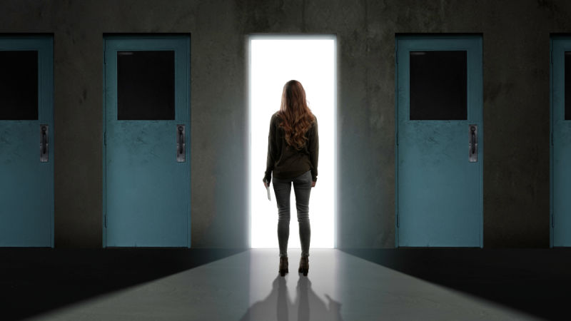 Woman stands before open door