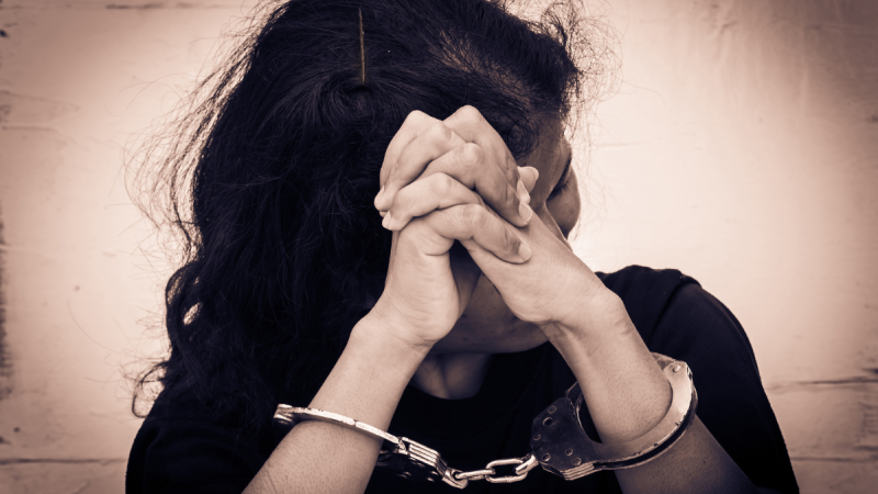 a woman in handcuffs hides her face