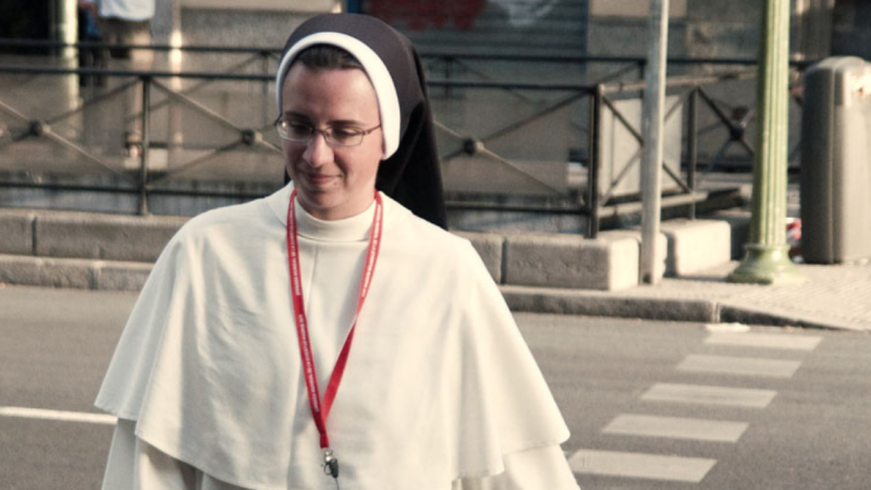 A sister in white habit crosses the street