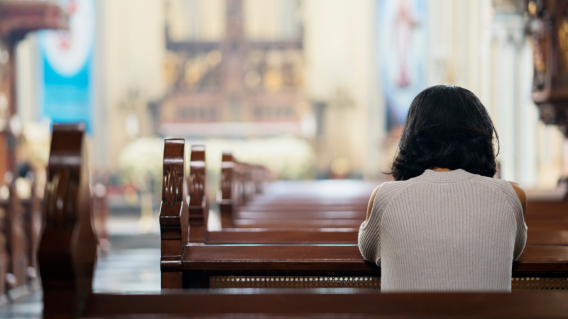 woman sits alone in back of church
