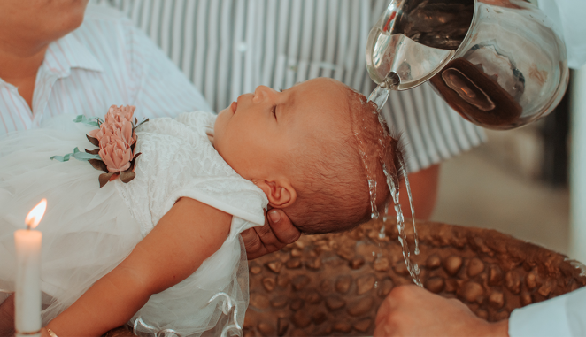 Holy water is poured over a baby's head as she is baptized.