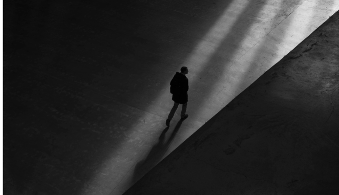a man walks by himself across a dark space
