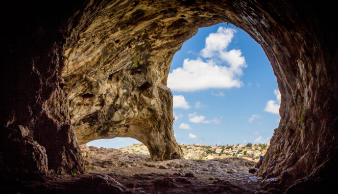 From inside a cave, a blue sky is visible